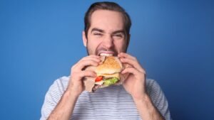 Alimentação para corredores: imagem de jovem comendo um sanduíche de maneira voraz.
