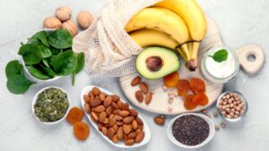 Imagem de alimentos variados sobre uma mesa: banana, abacate, oleaginosas, damasco etc.