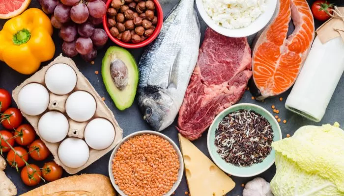 Imagem de mesa repleta de alimentos ricos em proteína animal e vegetal como carne, peixe, soja e ovos.