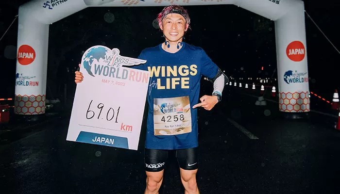 Atleta japonês mostra placa com inscrição de 69,9KM.