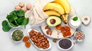 Imagem de alimentos variados sobre uma mesa: banana, abacate, oleaginosas, damasco etc.